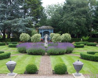 parterre garden with statue surrounded by lavender and standard trees in a design by Helen Taylor