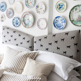 Plates in white bedroom above a bed