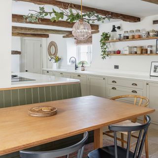 kitchen with oak table and banquette seating at the back is cream cabinetry with cup handles