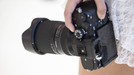 The Tamron 25-200mm f/2.8-5.6 DI III VXD G2 in a person's hand mounted on a camera