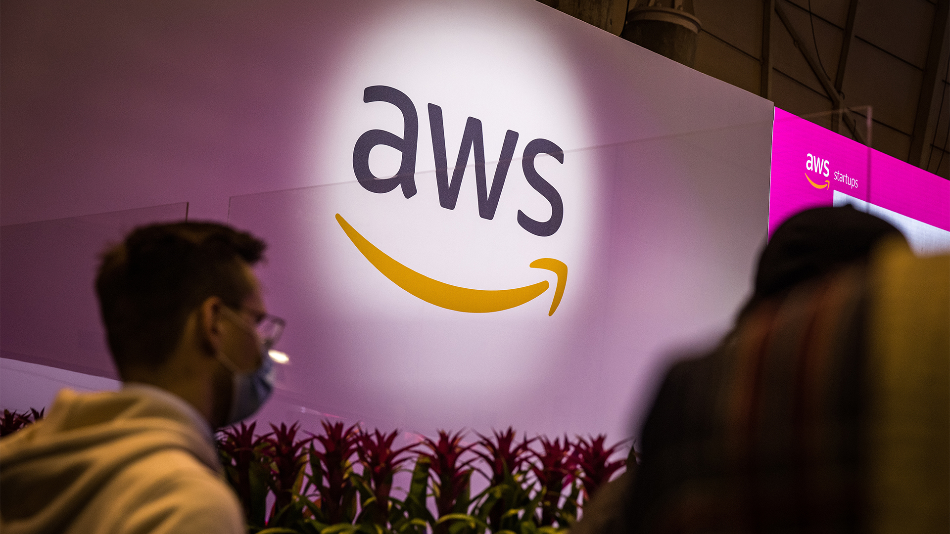 Amazon Web Services (AWS) logo projected onto a wall at the Web Summit conference in Lisbon as attendees walk by. 