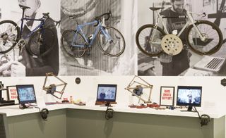 Desk with screens and headphones, with bikes mounted on the walls in front of images
