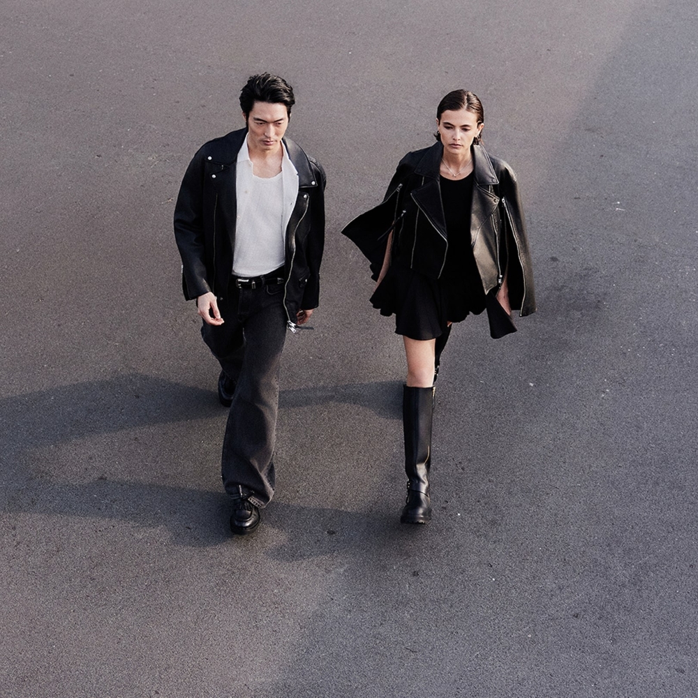 A male and female model from birds eye view wlaking down a road wearing outfits and jackets sold at AllSaints