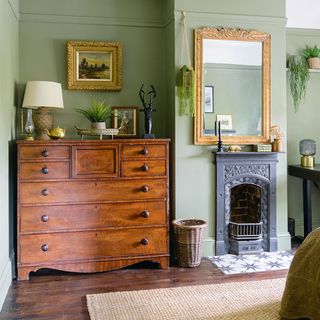 green bedroom with fireplace and chest of drawers
