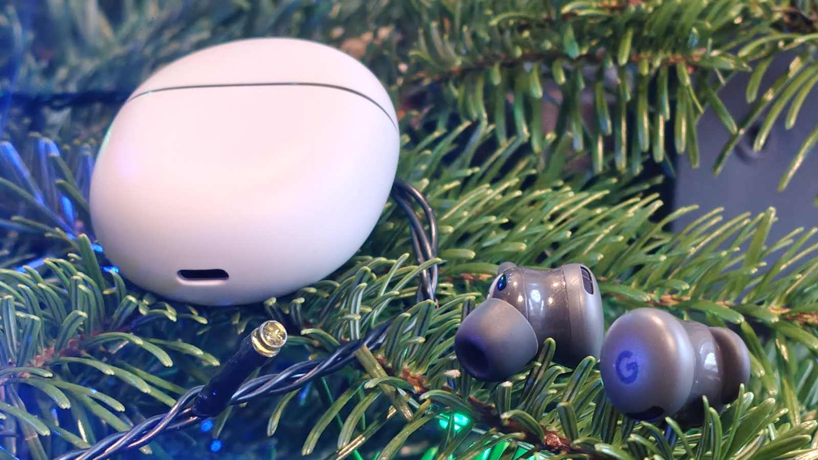The Google Pixel Buds 2a earbuds on a tree, with the case to the side.
