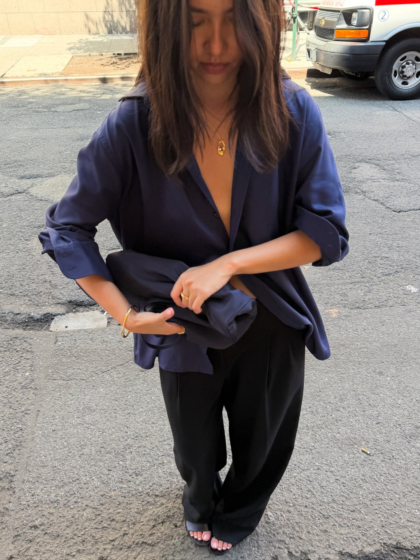 A woman wearing a chic outfit consisting of black trousers and a silky navy shirt