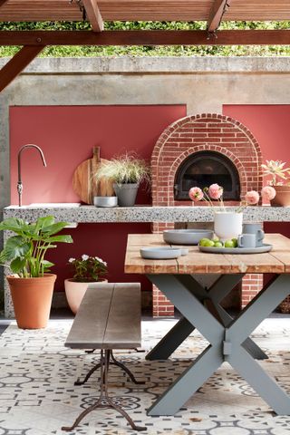 outdoor kitchen with pizza oven and red render walls