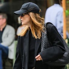 Julianne moore wears a baseball cap and a black blazer with a bottega veneta bag.