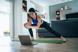 A woman working out at home in front of her laptop