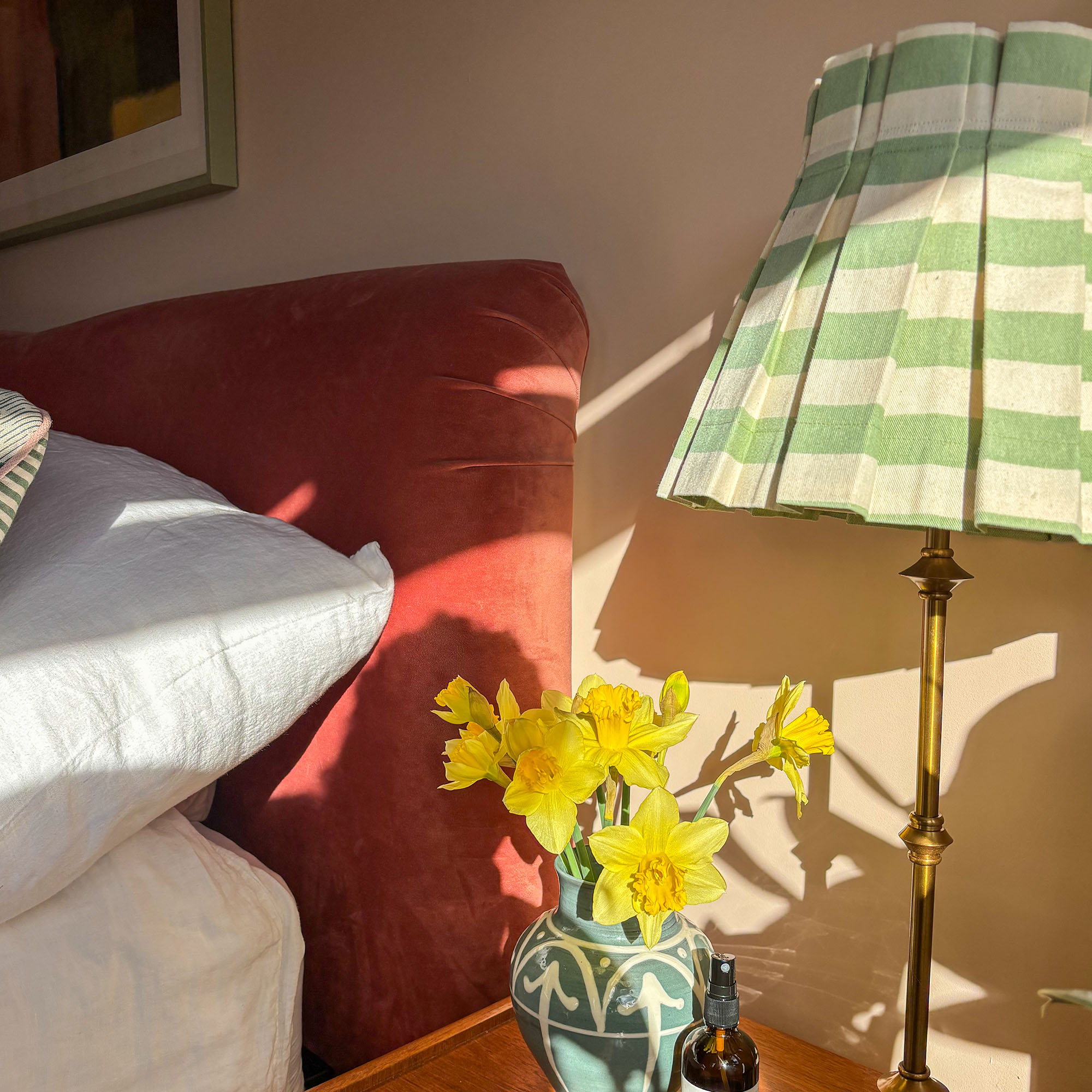 striped green lamp next to a red bed