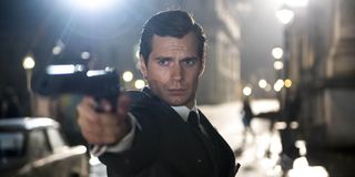 Napoleon Solo (Henry Cavill) points a gun while wearing a suit in 'The Man from U.N.C.L.E.'