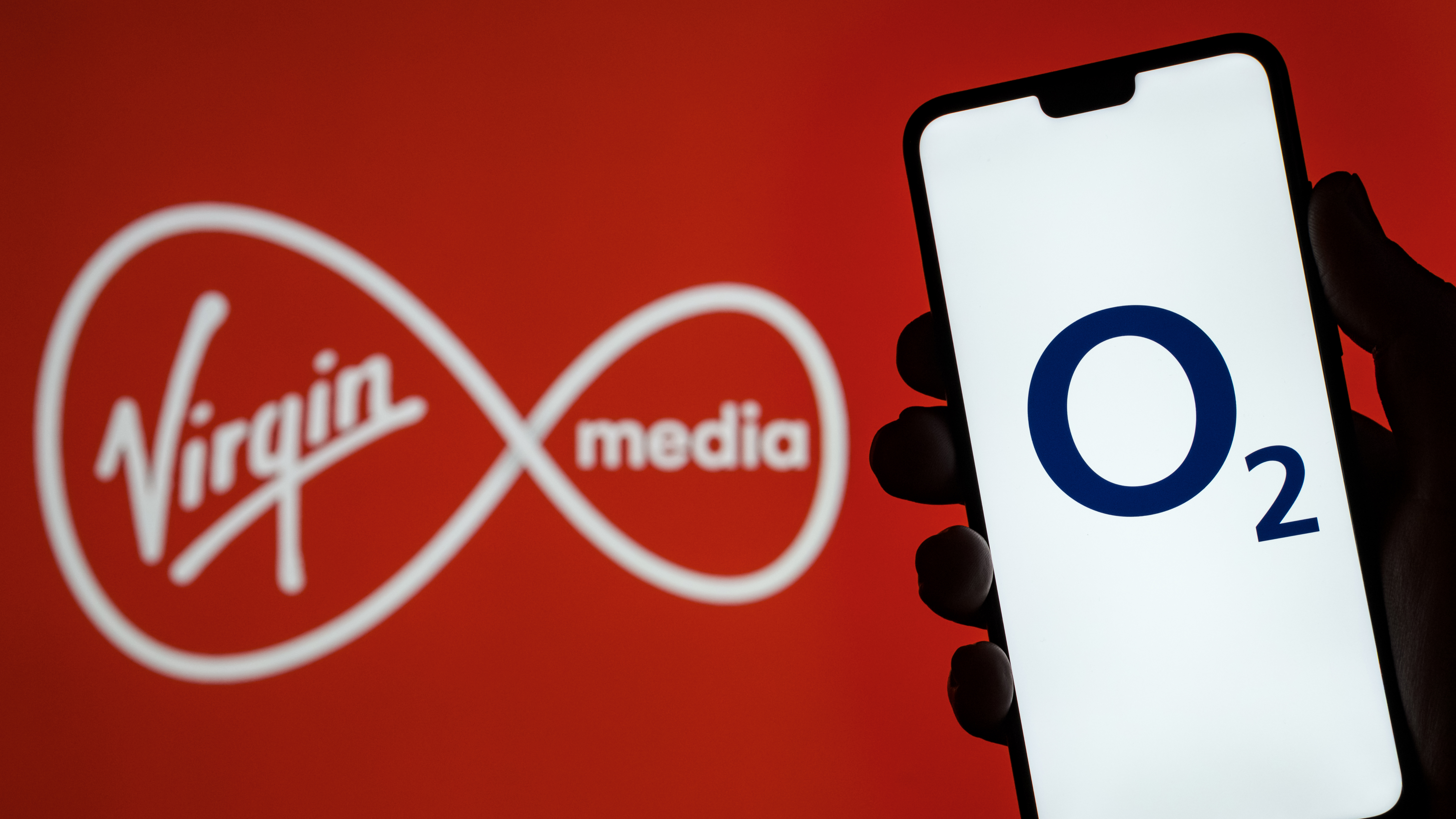 A Virgin Media logo next to a hand holding a phone with an O2 logo
