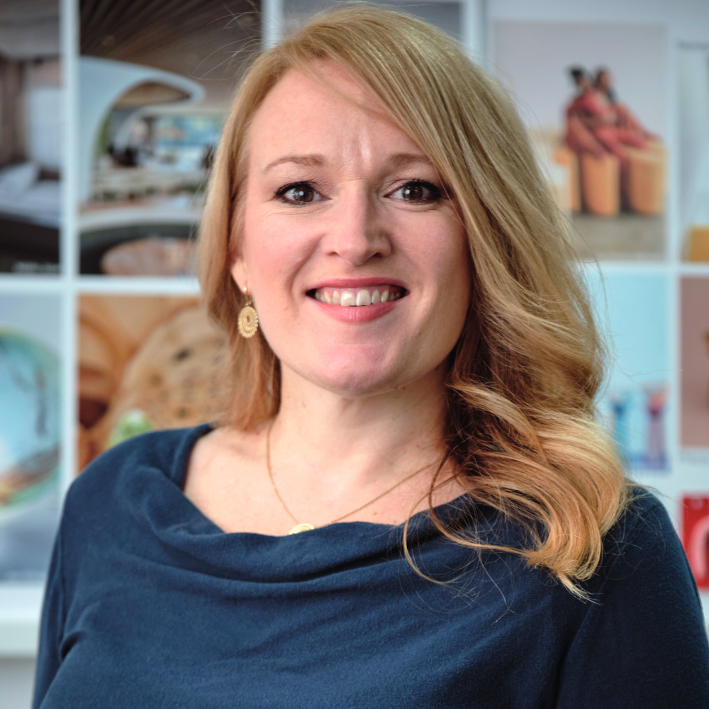 woman with long blond hair and navy top smiling at camera