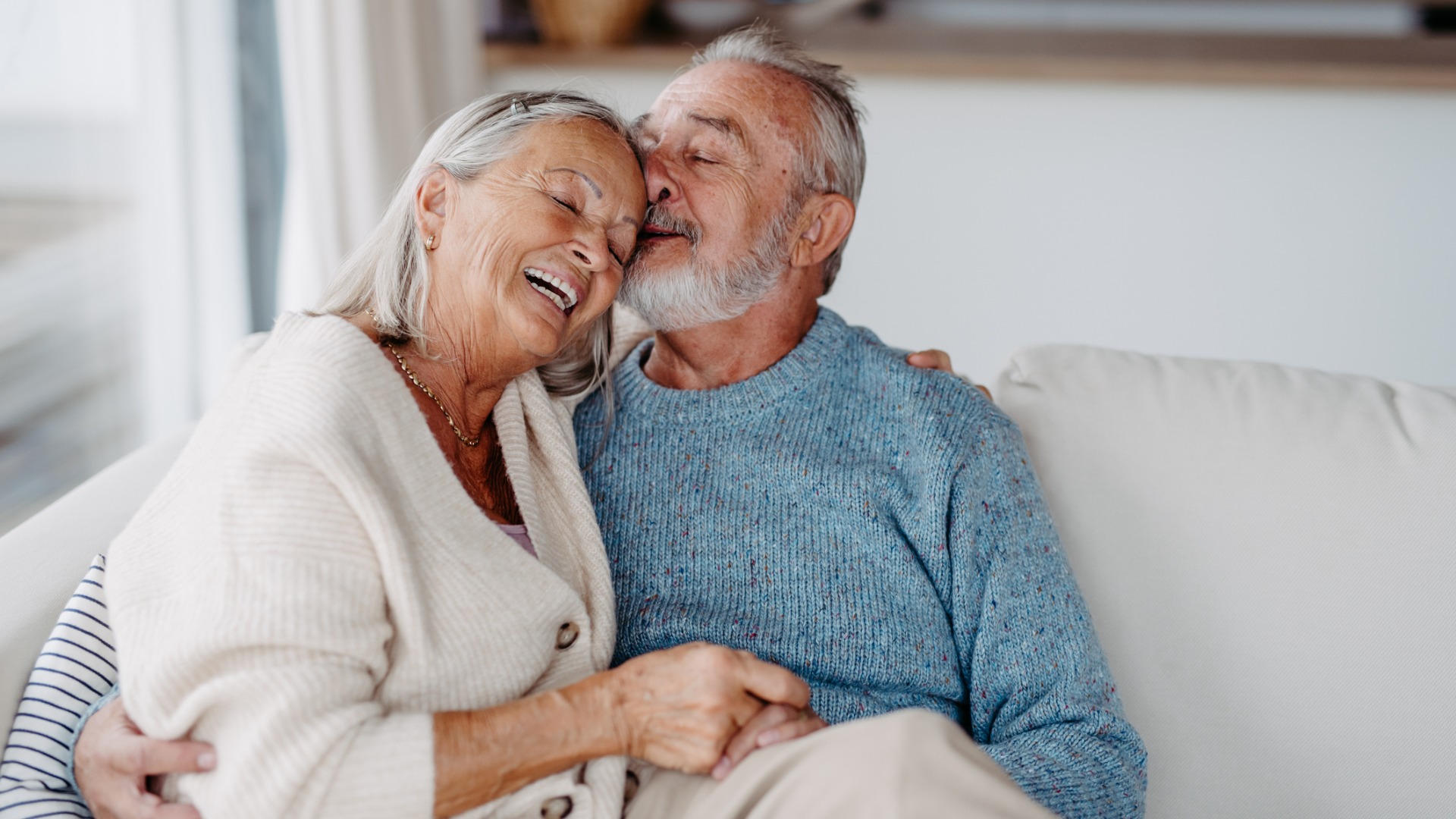 Older couple cuddling on the sofa