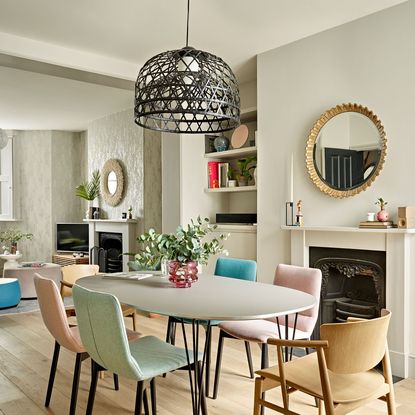 dining area with wooden floor and white wall and fireplace and round mirror and dining table and chairs