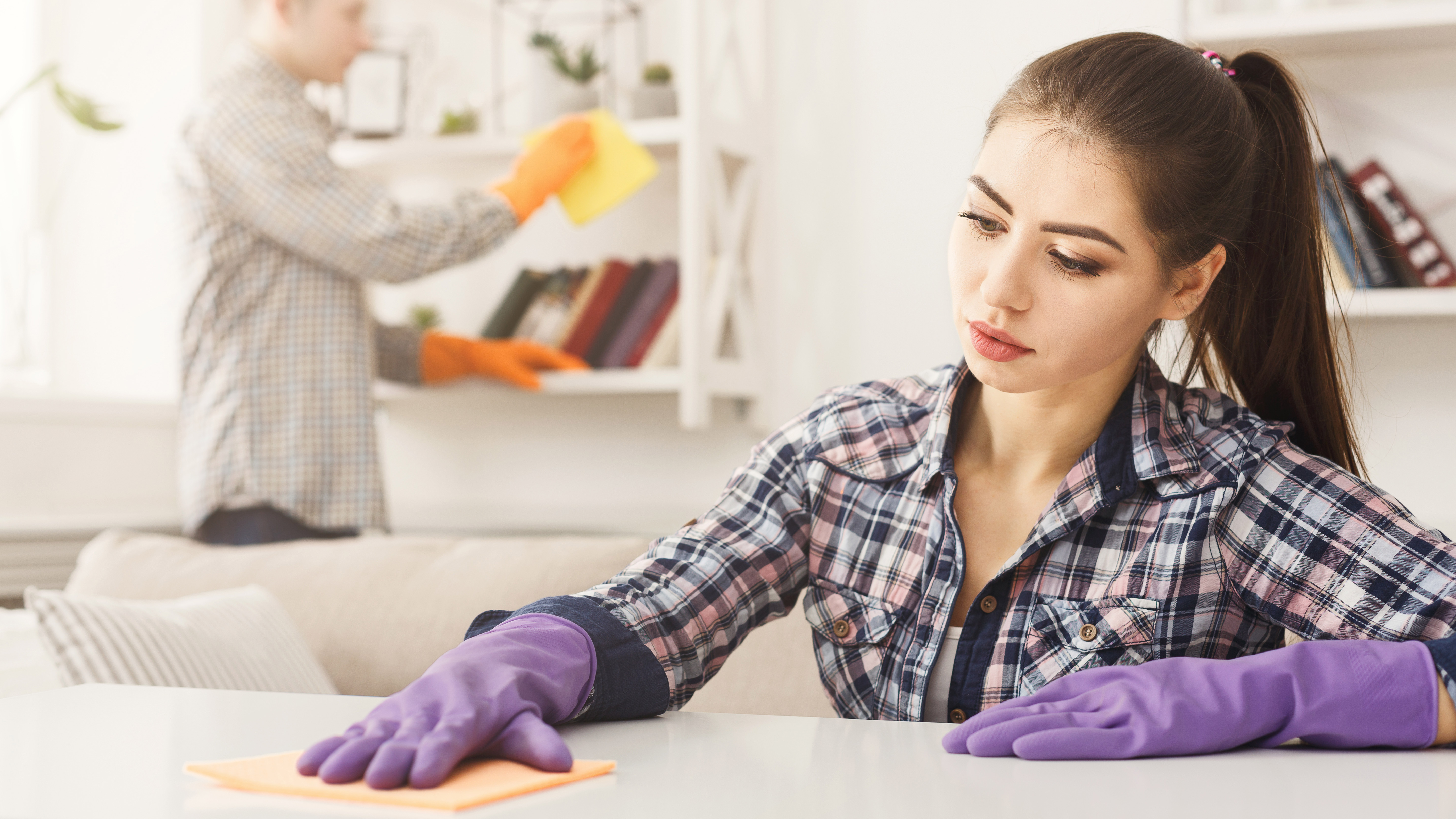 A young couple dusting a room in their home together