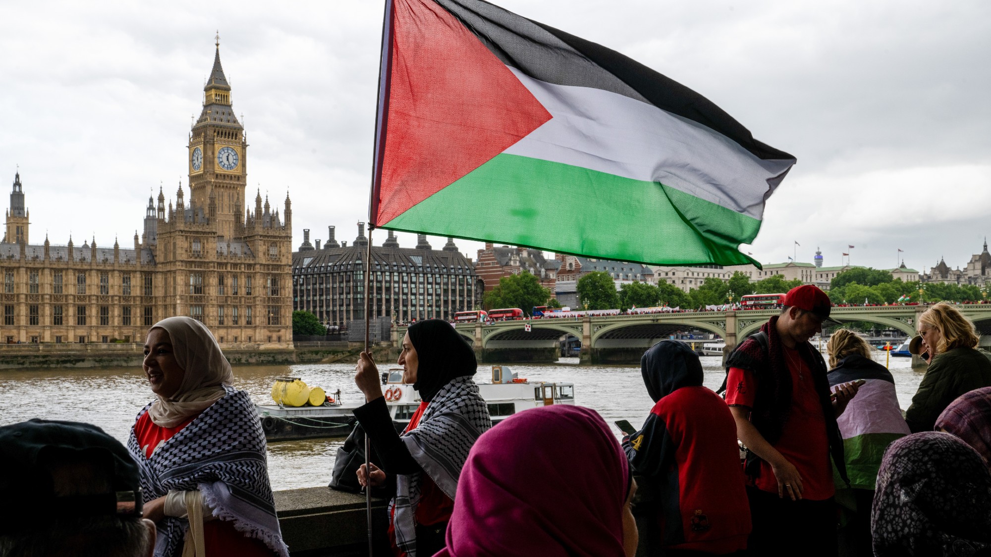 Protesters with Palestinian flags standing across the river from the Houses of Parliament in London