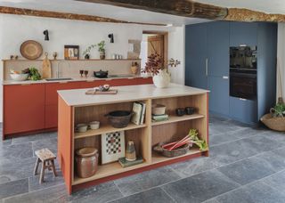 Open shelving in a kitchen island with a large blue cabinet on the right side of the kitchen. There is further open shelving above the sink