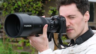Fujifilm GFX 100S II camera and GF 500mm lens held up to a man's face