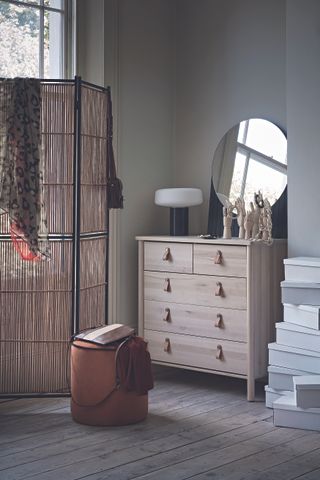 A bedroom with a wooden chest of drawers and a screen divider