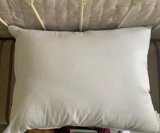 The Brooklinen Down Pillow on a chaise lounge.