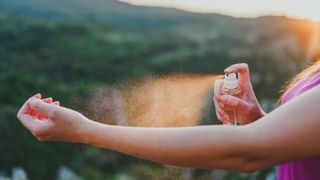 woman spraying spray on arm