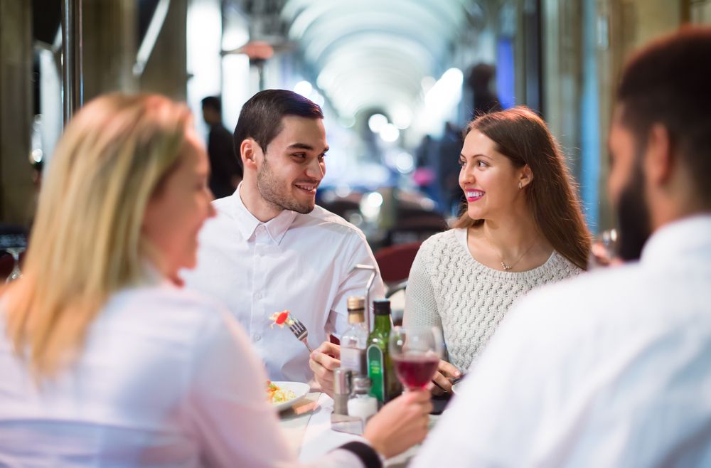 Two couples have dinner together.