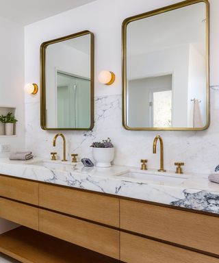 Mandy Moore's bathroom double sinks, featuring wood cabinets, marble countertops, and gold mirrors