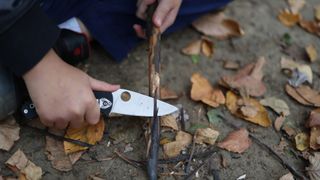 a camping knife cutting a stick