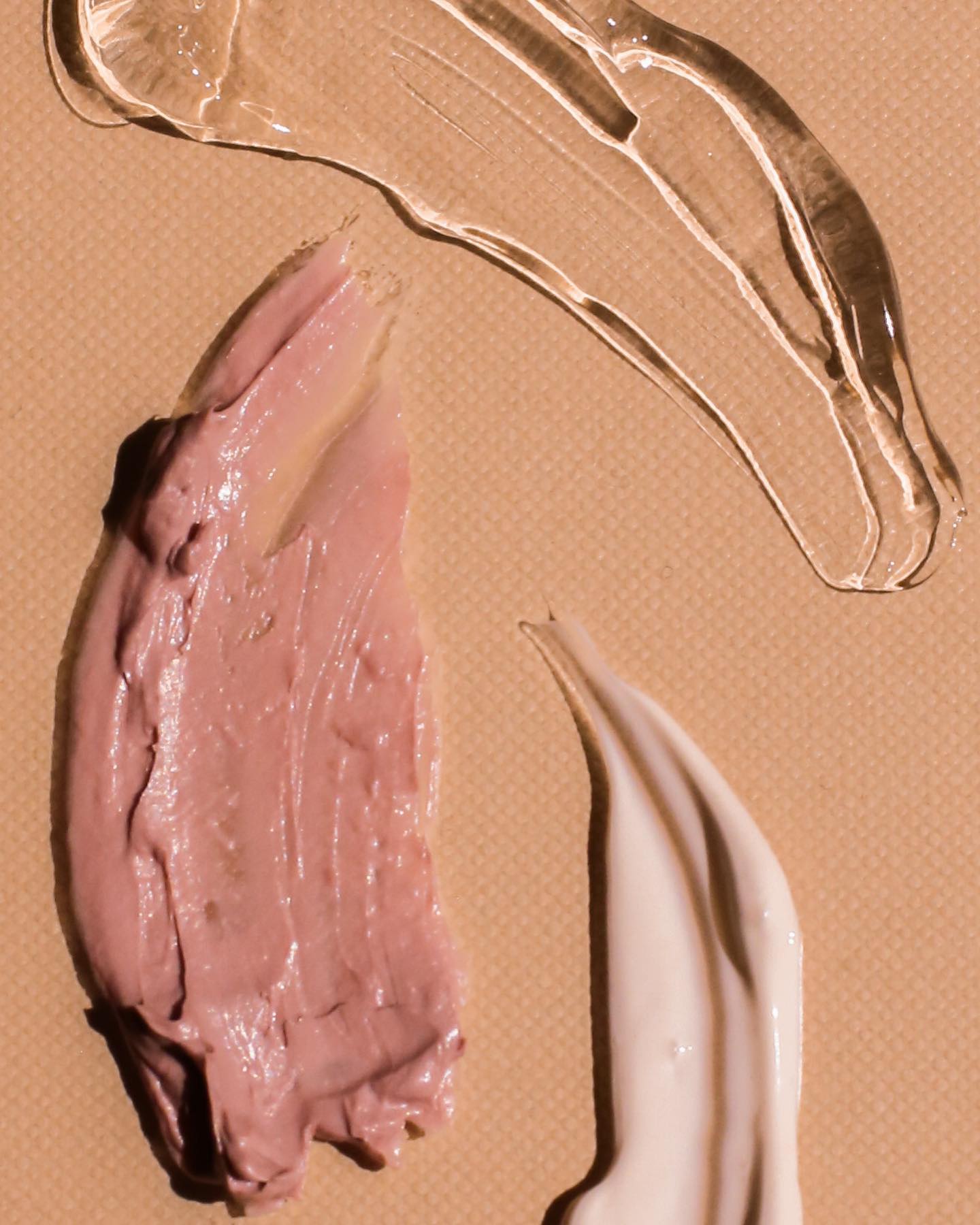 Pink serum-like swatches on a peach background