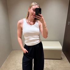 Woman wears white Tank top and navy blue linen trousers