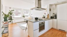 A bright white kitchen with island counter that isn't overwhelmed with small kitchen clutter