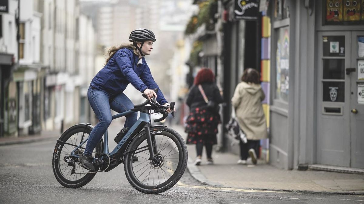 A woman riding a Canyon e-bike through city streets