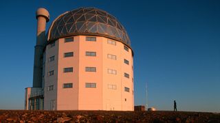 SALT (South African Large Telescope) is housed in a large white observatory with a large dome roof.
