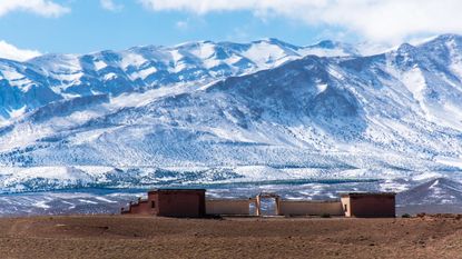 A photo of a snowy mountain range with a Moroccan building in the foreground
