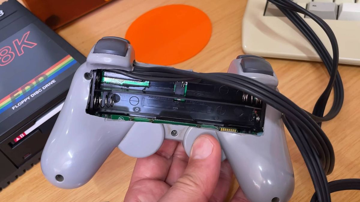 Back view of PlayStation PUGA PS1 plug-and-play controller console with battery compartment in view.