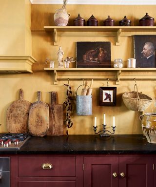 A red and yellow kitchen with shelves decorated with art