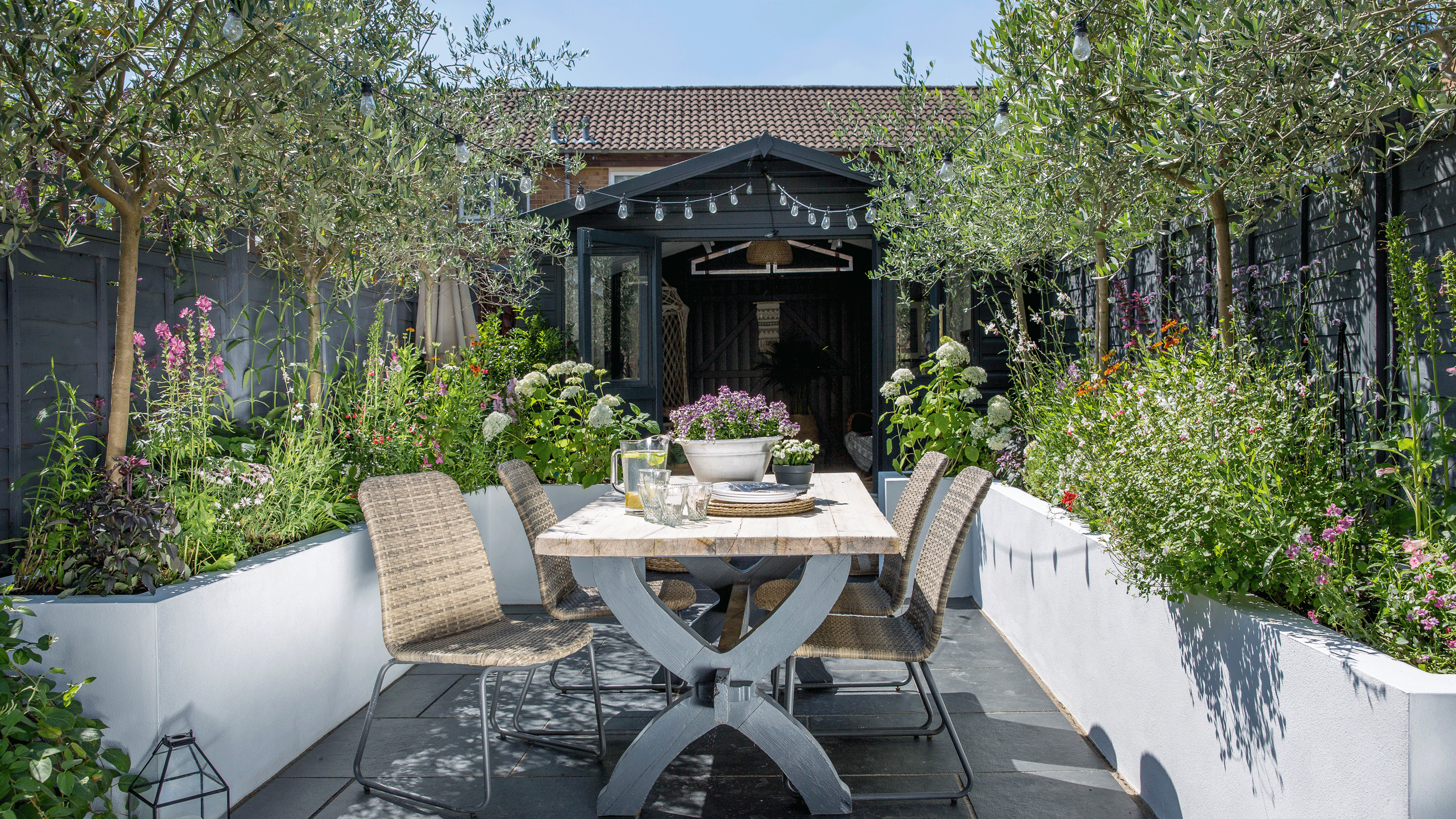 Patio with raised garden beds with festoon lights hanging over dining table