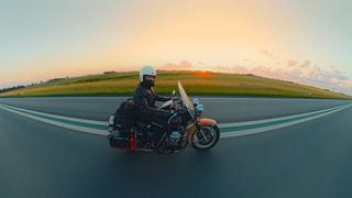A man on a bike holds an action camera out beside him to take a picture of the road