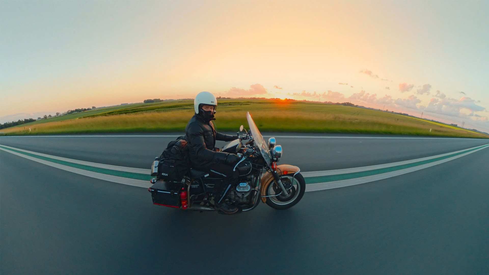 A man on a bike holds an action camera out beside him to take a picture of the road