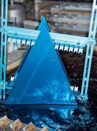 View of a triangle for the installation being dipped into an anodising tank. The triangle is blue