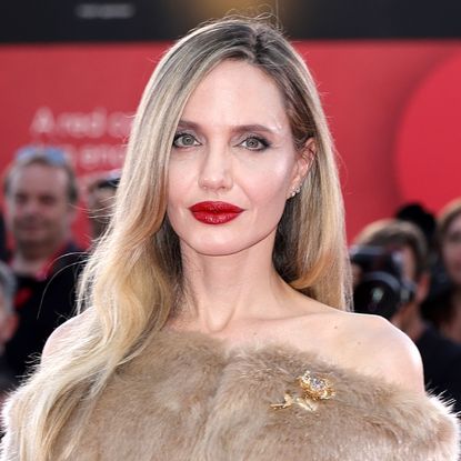 Angelina Jolie wears a fur off-the-shoulder shawl coat on the red carpet