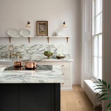 marble and white kitchen with open plan shelving, wall lights, marble work tops, dark painted island