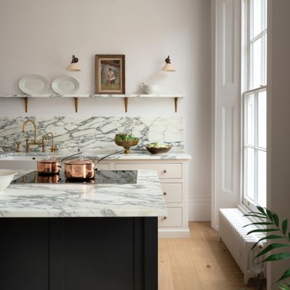 marble and white kitchen with open plan shelving, wall lights, marble work tops, dark painted island
