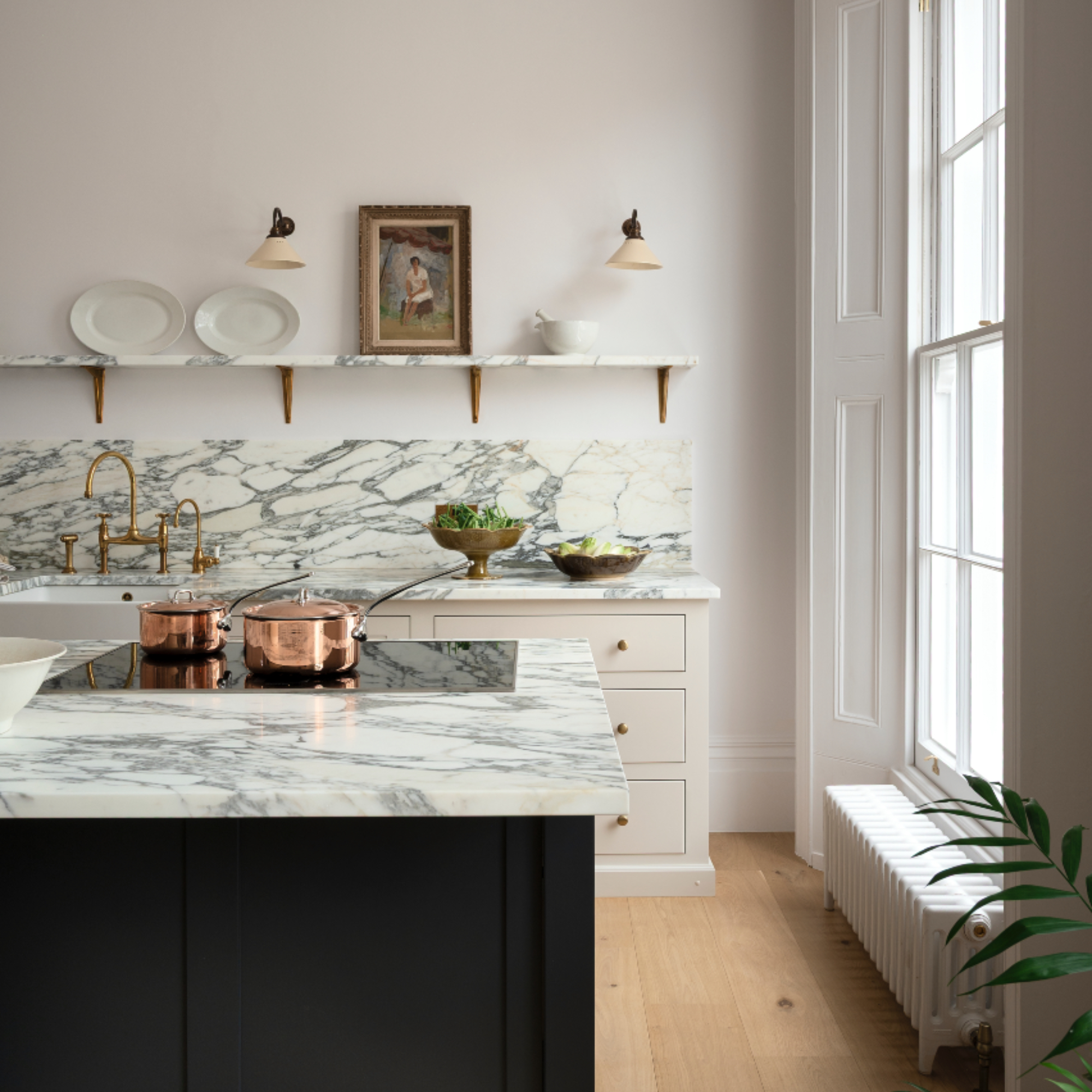 marble and white kitchen with open plan shelving, wall lights, marble work tops, dark painted island