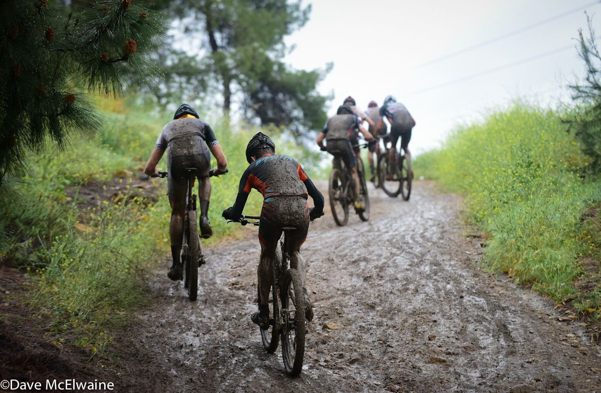 Racers climbing a muddy fire road during lap four