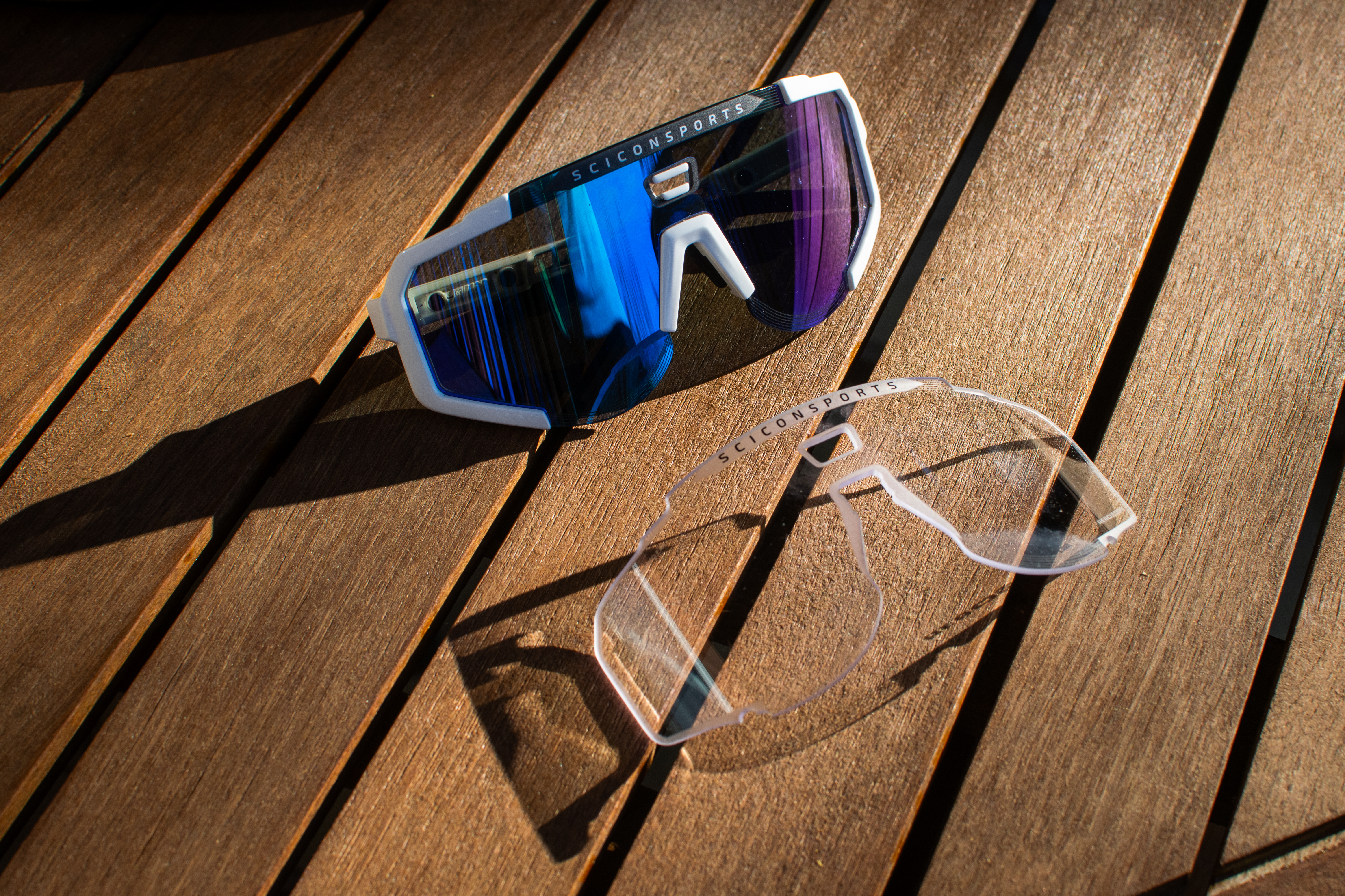 A pair of scicon aeroscope sunglasses and clear lens on a wooden table
