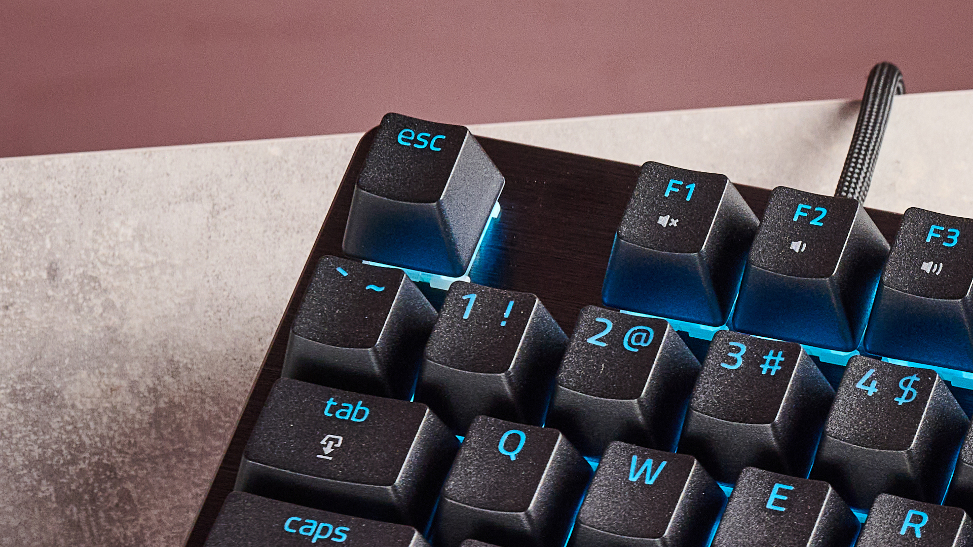 Close-up of escape key on Razer Huntsman V3 HE Magnetic Tenkeyless 8KHz, on desk with pink wall in background