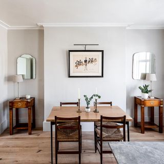 dinning area with white wall wooden dinning table and chairs frames on wall