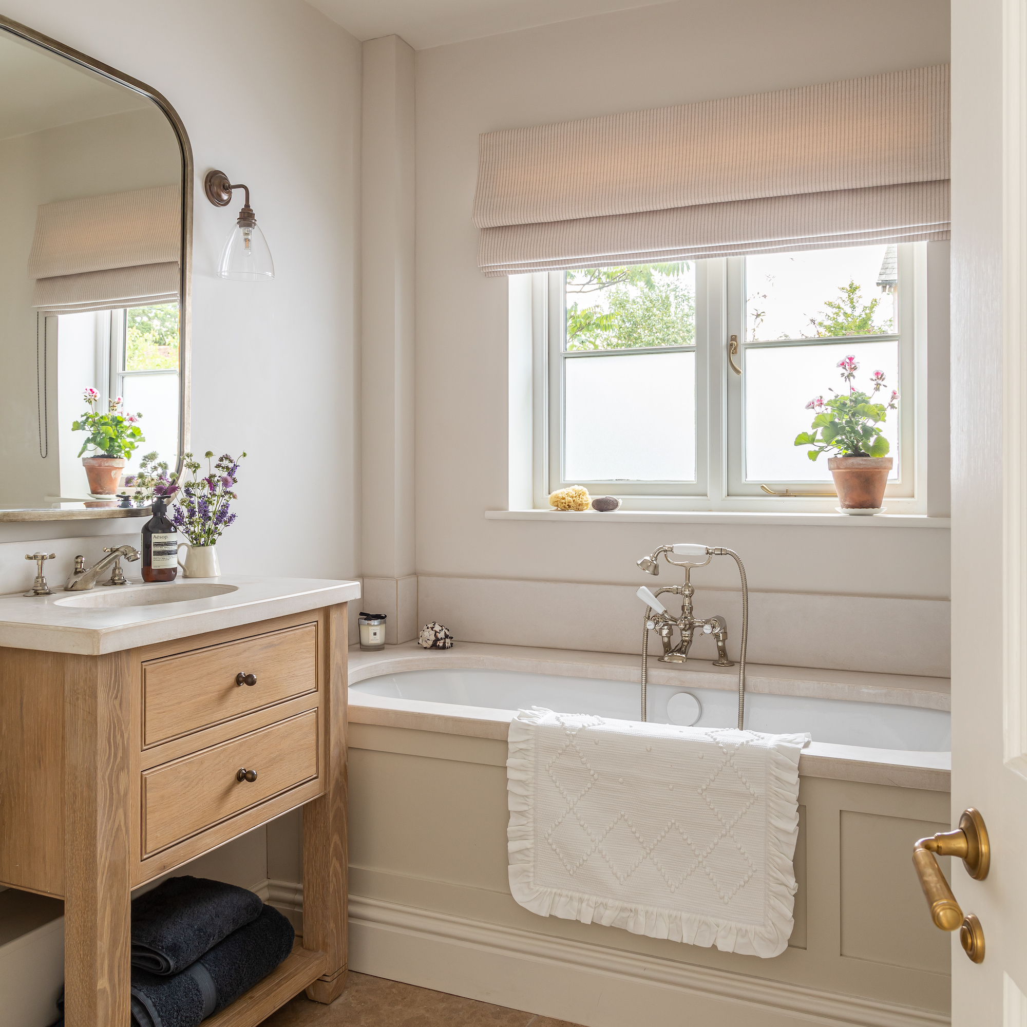 neutral coloured bathroom with wooden vanity unit with brass framed mirror